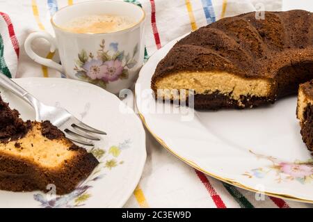 Ein Stück marmorierter Kuchen auf einem Teller mit einer Tasse Kaffee auf einem farblichen Hintergrund Stockfoto