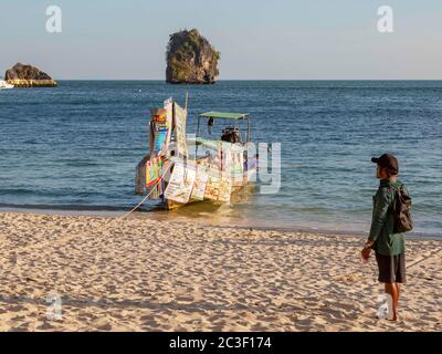 Krabi, Thailand - 14. Februar 2019: Schwimmender Markt. Verkauf von Speisen und Getränken von Booten. Menü am Heck des Schiffes. Mann, der zum Boot schaut. AO Phra Nang Strand, Ende des Arbeitstages. Stockfoto