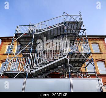 Riesige Feuerflucht vor einem gelblichen Gebäude unter einem blauen Himmel mit Weitwinkel-Optik Stockfoto