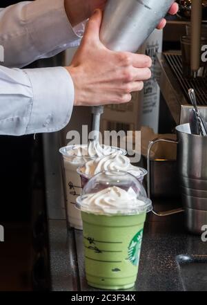 Barista, der Gäste im Starbucks Coffee House, Nakameguro Station, Tokio, Japan, mit einem Getränk zubereitet Stockfoto