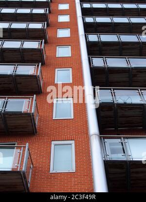 Blick nach oben auf modernes Apartmentgebäude mit Fenstern in Ziegelwänden und Glasbalkonen Stockfoto