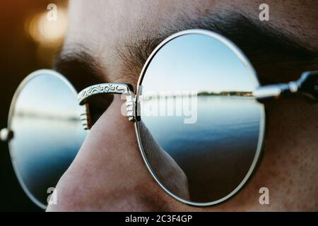 Verspiegelte Sonnenbrillen spiegeln die verträumte Seeseite aus der Nähe stilvoll wider Stockfoto