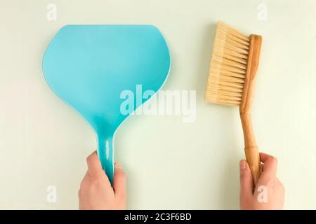 Plastikschaufeln und Holzbürste in Frauenhänden. Stockfoto