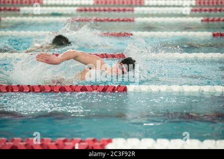 Ein junger männlicher Schwimmer der Oberstufe schwimmt während eines Schwimmmeet in Freestyle Stockfoto