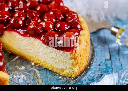 Käsekuchen mit Kirschholzbelag auf blauem Holzhintergrund schneiden. Nahaufnahme. Stockfoto