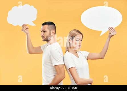 Verärgert Frau und Mann halten Papier Gedanken Blasen über gelben Hintergrund Stockfoto