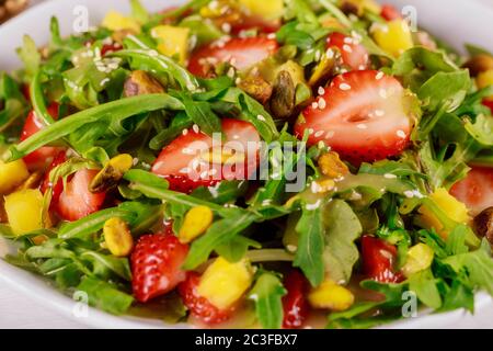 Grüner Salat mit Rucola, Erdbeeren, Mango und Pistazien. Nahaufnahme. Stockfoto