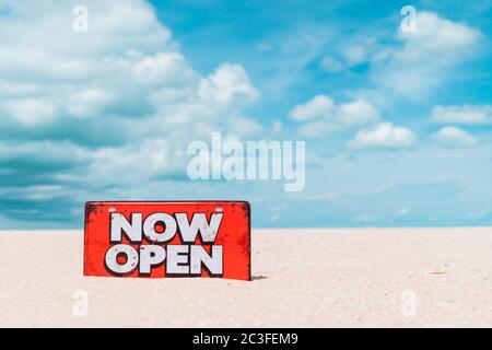 Jetzt offene Schild stehen auf Sand Sommer Strand Hintergrund Metapher zu Zeit zu reisen entspannen Tourismus Saison mit Copyspace Hintergrund. Stockfoto