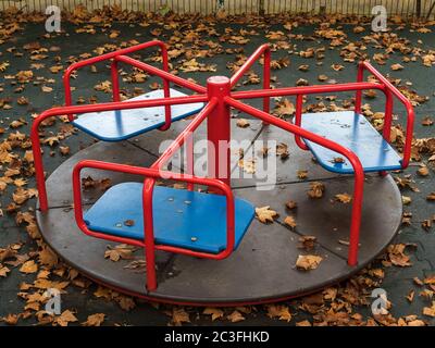 Runde Schaukel im Spielplatz mit gelben Blättern bedeckt Stockfoto