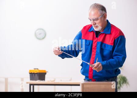 Ein alter Zimmermann, der drinnen arbeitete Stockfoto