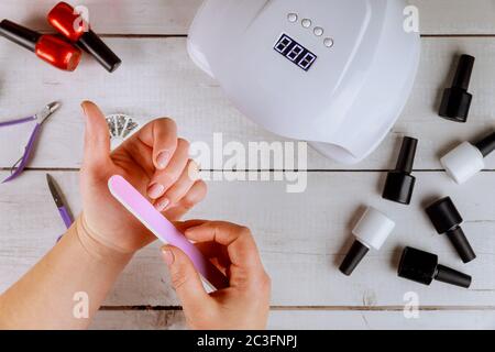 Frau macht Nagelmaniküre mit Nagelbrett oder Nagelfeile. Stockfoto