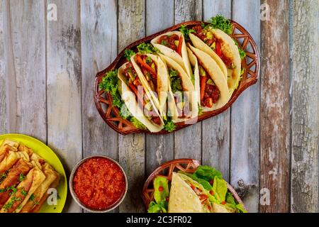 Taquitos, weiche Tortillas und milde Salsa auf Holztisch. Stockfoto
