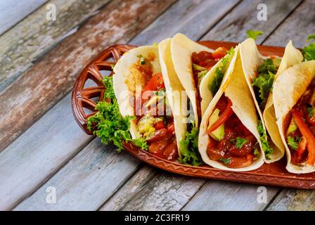 Mehl Tortillas gefüllt mit Fleisch, Bohnen und Gemüse auf Holzgrund. Lateinamerikanische Küche. Stockfoto