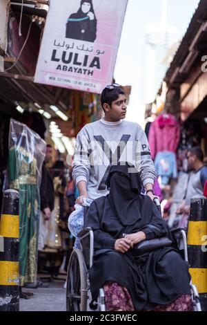 Manama / Bahrain - 10. Januar 2020: Einheimische muslimische Frau im Rollstuhl in traditioneller Kleidung Einkaufen in Manama Souq, auch ein berühmtes Touristenziel in der Hauptstadt von Bahrain Stockfoto
