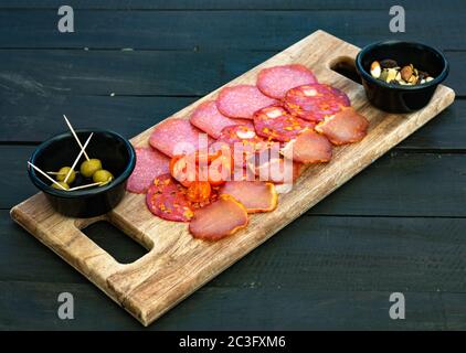 Platte für ausgehärtetes Fleisch. Chorizo, Salami, Schinken, Oliven auf einem Holzbrett. Stockfoto