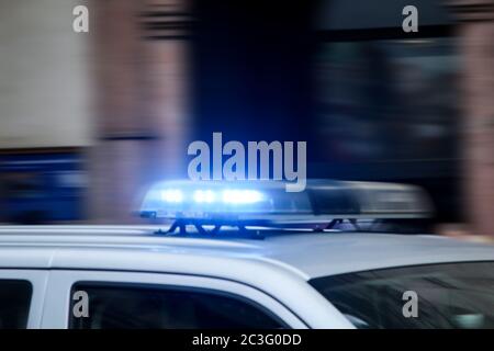 Ein Polizeiauto mit blinkenden Lichtern fährt schnell vorbei. Stockfoto