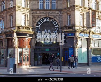 Menschen, die am Eingang zu den Leeds City Markets, einem historischen überdachten Marktgebäude in Leeds, West yorkshire, vorbeilaufen Stockfoto