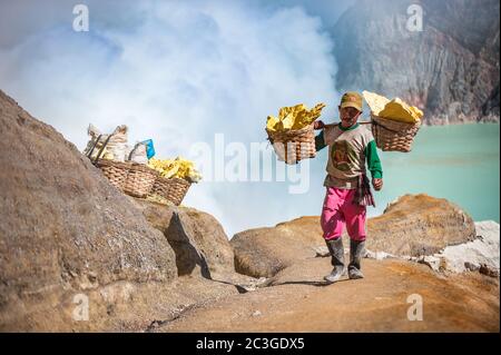 Kawah Ijen, Java, Indonesien - 6. August 2010: Schwefel-Bergmann mit schwefelhaltigen Körben am Kawah Ijen Vulkan in Ost-Java, Ind Stockfoto