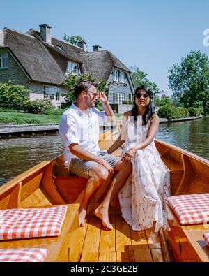 Giethoorn Niederlande Paar besuchen das Dorf mit einem Boot, Blick auf das berühmte Dorf mit Kanälen und rustikalen Strohdachhäusern i Stockfoto