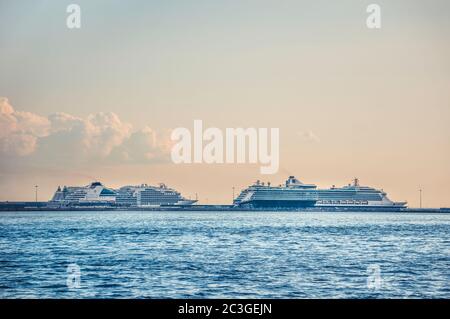 Ferne Kreuzfahrtschiffe vertäuten im Seehafen bei Sonnenuntergang Stockfoto