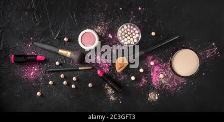 Professionelles Make-up über dem Kopf Panoramafoton auf dunklem Hintergrund. Pinsel, Lippenstift und andere Produkte, eine flache Lage Stockfoto