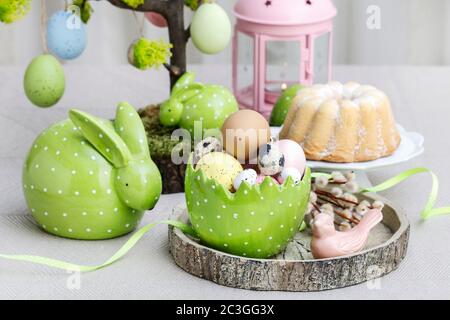 Ostertisch-Dekorationen mit bemalten Eiern und Keramikfiguren. Festliche Zeit Stockfoto