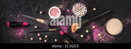 Professionelles Make-up-Panorama auf dunklem Hintergrund. Pinsel, Lippenstift und andere Produkte, eine flache Lage Stockfoto