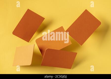 Dicke orangene Visitenkarten mit abgerundeter Ecke, schwebend auf einem gelben Papierhintergrund, ein Modell für ein kreatives Design-Geschenk Stockfoto