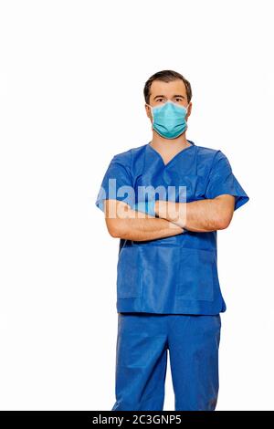 Männliche Arzt in Scrubs trägt schützende Gesichtsmaske und Handschuhe mit Kreuzhände warten auf Patienten Stockfoto