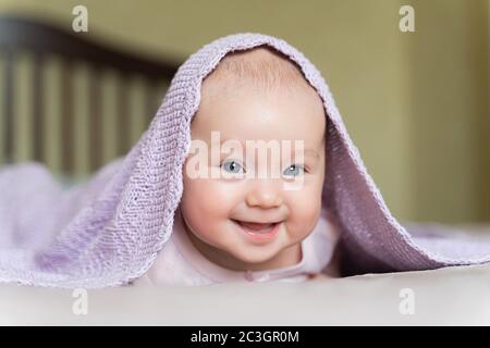 Ein schönes neugeborenes blauäugiges Mädchen liegt auf ihrem Bauch und lächelt Stockfoto