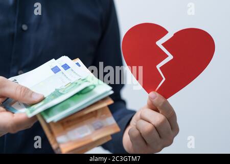 Mann hält Geld und ein gebrochenes Herz - das Konzept der Liebe und Geld Stockfoto