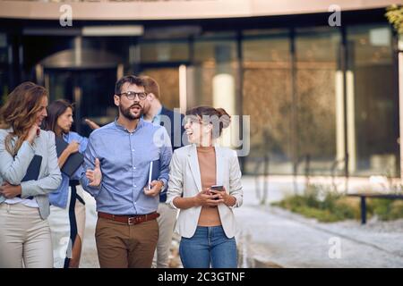 Zugeschnittenes Bild von kaukasischen Geschäftsleuten, die spazieren, reden und lachen Stockfoto