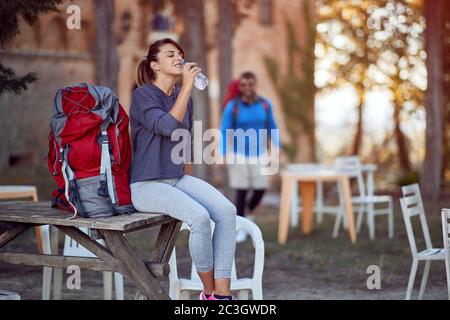 Durstige junge kaukasische weibliche Trinkwasser, sitzend, eine Pause vom Wandern Stockfoto