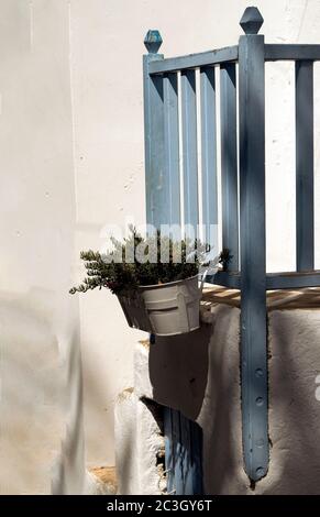 Ein traditioneller, altmodischer Balkon in einem Dorfhaus auf der griechischen Insel Folegandros. Frische Kräuter wachsen in einem Topf bei den Schritten. Stockfoto