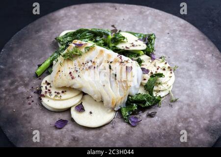 Gourmet-frittiertes europäisches Kabeljau-Fischfilet mit Rapini-Brokkoli rabe und Creoxetti-Pasta als Nahaufnahme auf einem modernen Design-Teller Stockfoto