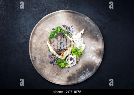 Gourmet gebratenes europäisches Skrei Kabeljau Fischfilet mit Rapini Brokkoli rabe und Nudeln als Draufsicht auf einem modernen Design Teller mit Kopie Stockfoto