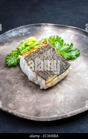 Gourmet-gebratenes europäisches Skrei-Kabeljau-Fischfilet mit Rapini-Brokkoli-rabe als Nahaufnahme auf einem modernen Design-Teller Stockfoto