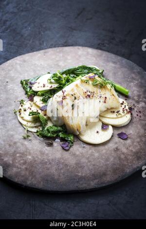 Gourmet-frittiertes europäisches Kabeljau-Fischfilet mit Rapini-Brokkoli rabe und Creoxetti-Pasta als Nahaufnahme auf einem modernen Design-Teller Stockfoto