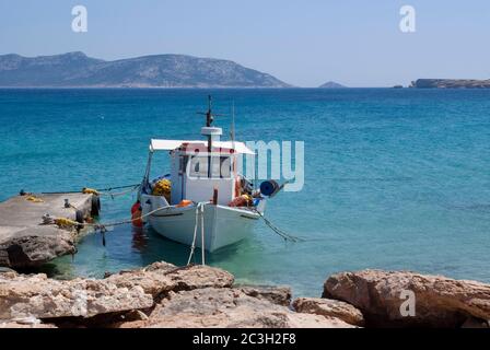 Ein kleines Fischerboot, das an einem Steg auf der schönen griechischen Insel Koufonissi festgemacht ist. Kristallklares blaues Wasser und Sonnenschein, in diesem entspannenden und frie Stockfoto