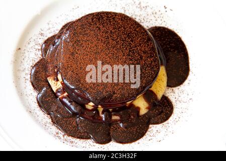 Pfannkuchen mit Schokolade bestreut mit Schokoladenpulver auf einem weißen Teller Stockfoto