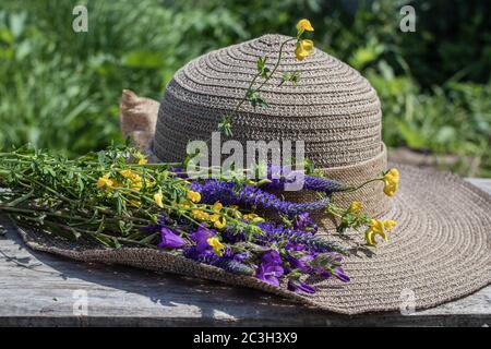 Sommerkomposition. Ein Strauß wilder Blumen und ein Sonnenhut für Frauen. Nahaufnahme. Stockfoto