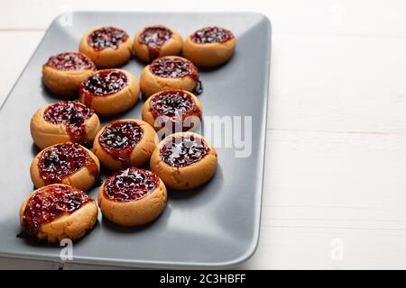 Süße Beerengelee-Kekse auf grauem Teller auf weißem Hintergrund. Stockfoto