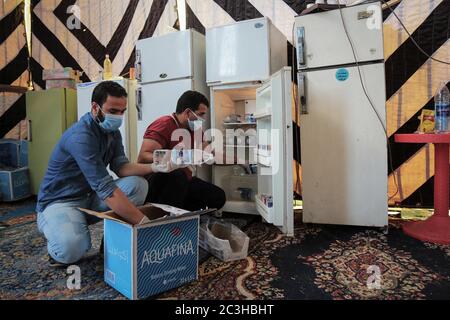 El Rahmaniya, Ägypten. Juni 2020. Zwei Männer stapeln einen Kühlschrank mit Wasserflaschen in einem Feldlazarett in der Stadt El Rahmaniya im nordägyptischen Beheira Governorate, das durch Spenden von Einheimischen gebaut wurde, um Coronavirus-Patienten zu isolieren und zu behandeln. Das Krankenhaus wurde von lokalen freiwilligen Krankenschwestern und Ärzten betrieben und nach der Genehmigung von Behörden gebaut, jedoch empfängt es keine Patienten über 50 Jahren oder kritische Fälle. Kredit: Fadel Dawood/dpa/Alamy Live Nachrichten Stockfoto