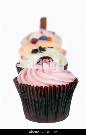 Cupcakes-Reihe auf weiß isoliert. Absichtlich geringe Schärfentiefe. Stockfoto