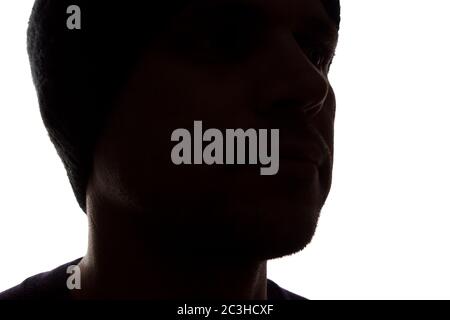 Porträt eines jungen Mannes, unrasiert, Seitenansicht in Mütze - dunkel isolierte Silhouette Stockfoto