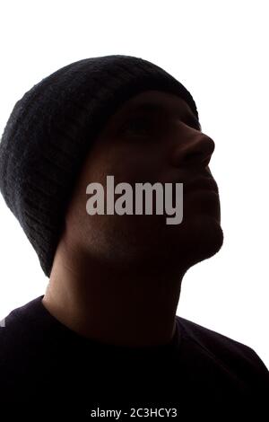 Porträt eines jungen Mannes, unrasiert, Seitenansicht in Mütze - dunkel isolierte Silhouette Stockfoto