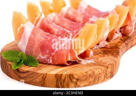 Parmaschinken und Melonenscheiben auf Olivenholzplatte über Weiß serviert Stockfoto