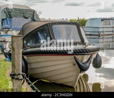 Vorderansicht eines kleinen Motorbootes, das in einem privaten Liegeplatz vor dem Thurne Dyke im Norfolk Broads National Park festgebunden ist Stockfoto