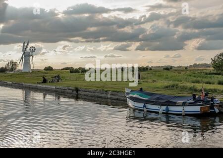 Thurne Dyke vor dem Rver Thurne im Norfolk Broads National Park, wenn die Sonne an einem bewölkten Abend untergeht Stockfoto