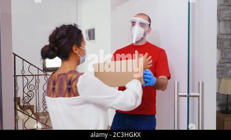 Kurier mit Schutzmaske, die das Paket an den Kunden liefert. Stockfoto